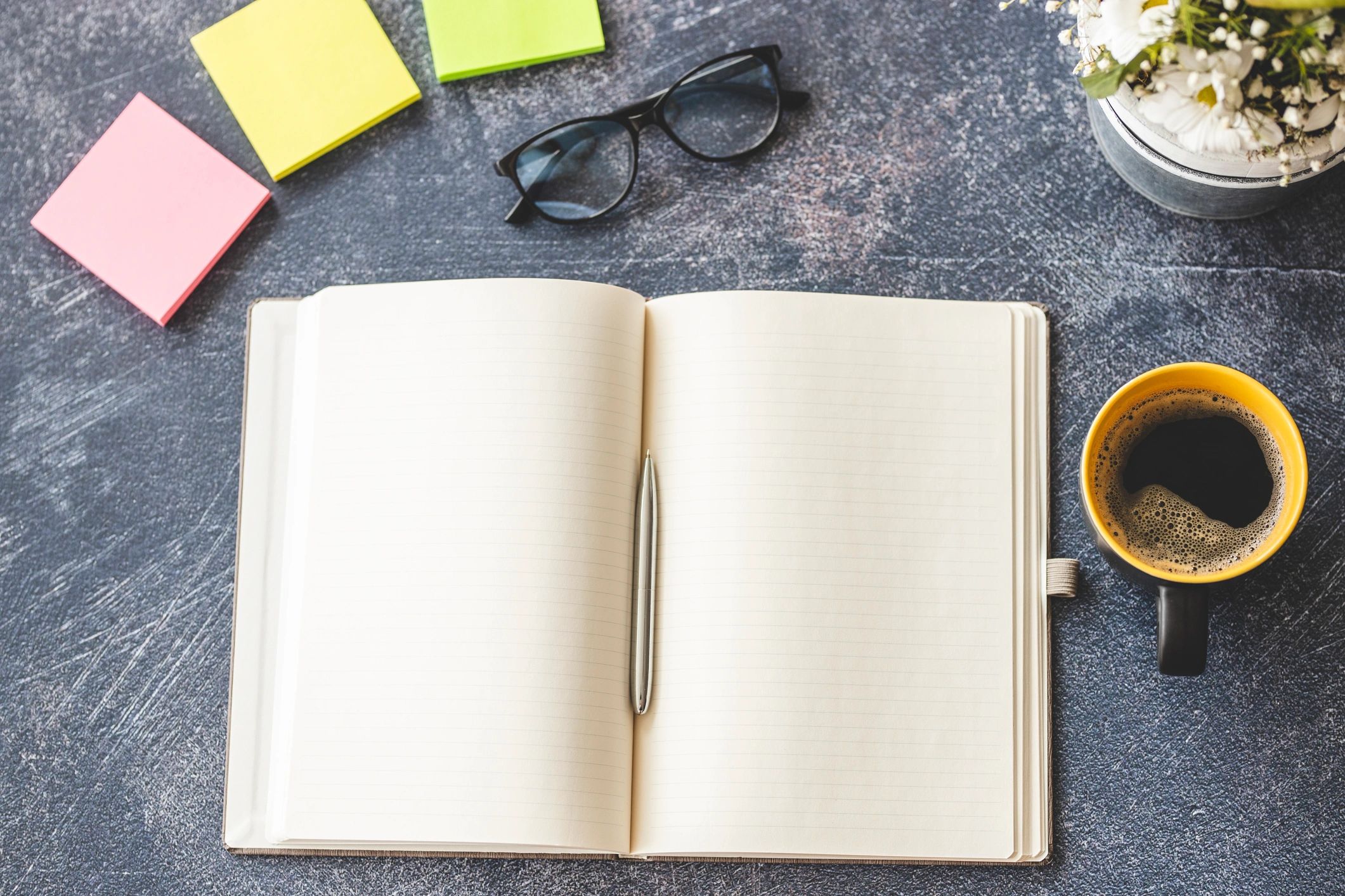 Empty notebook, coffee, and eyeglasses on a desk