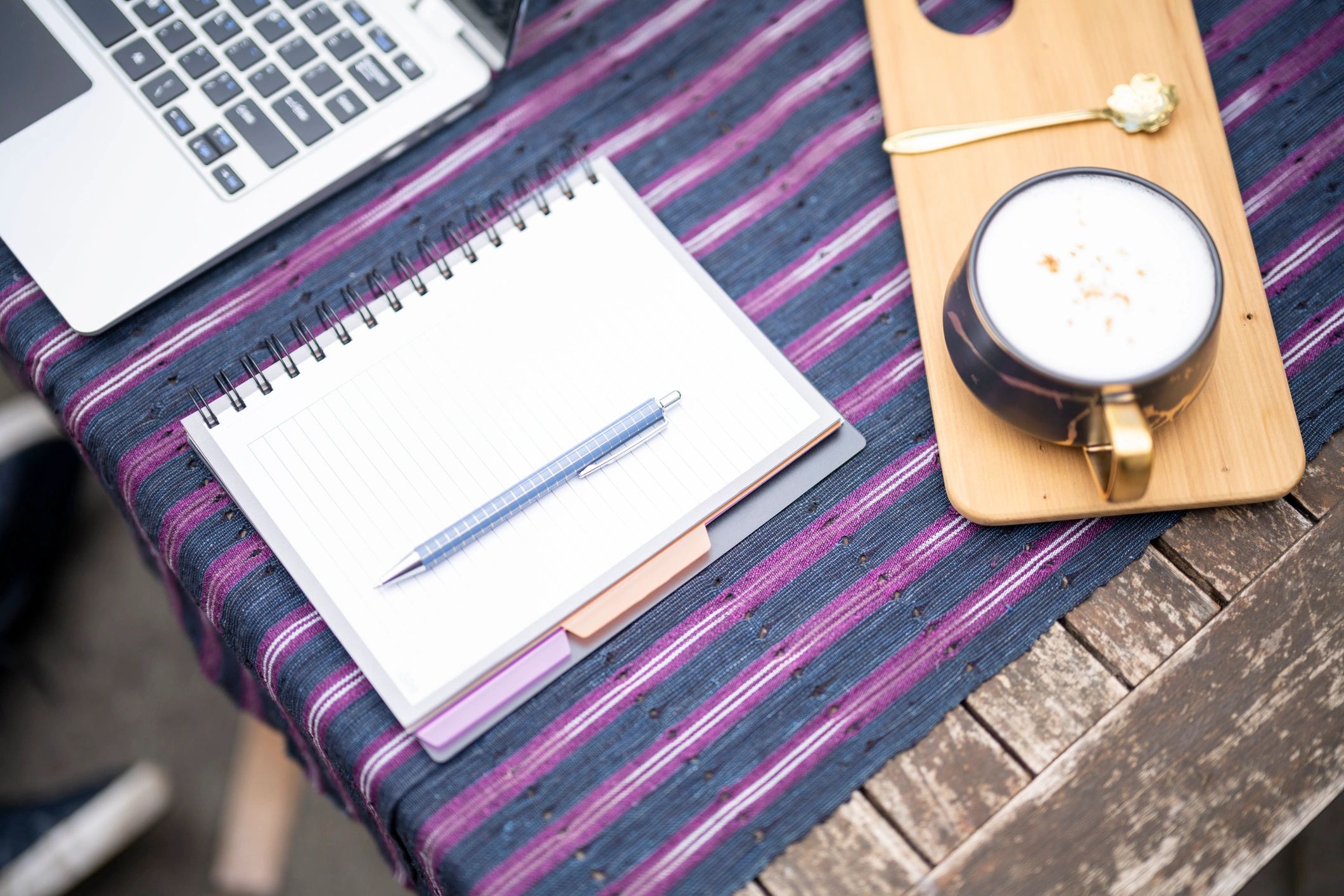 Notebook and pen next to laptop on a coffee table for study planning