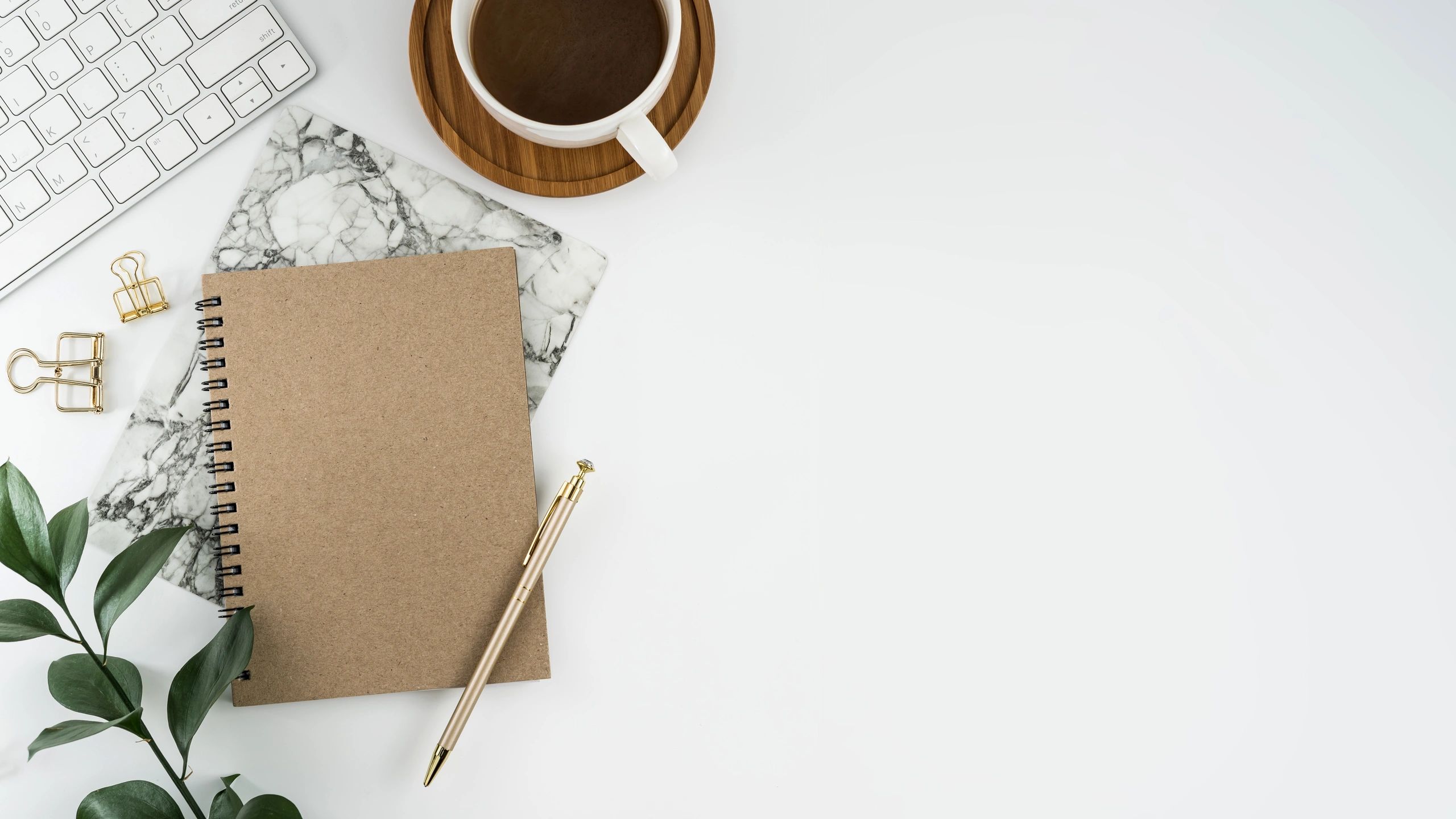 White desk with notebook, computer, and coffee cup